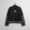 Black jacket with visible branding on a pegboard background
